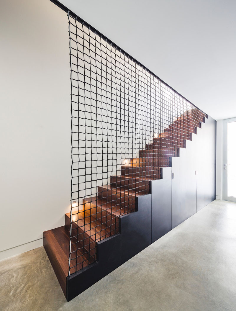These black and wood stairs with built-in storage, and a wire mesh net, that is not only visually interesting, it also acts as a safety barrier.