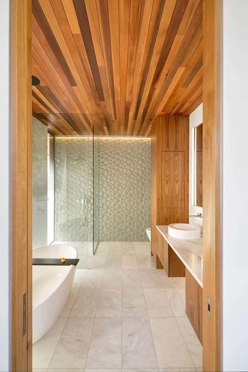 Wood, simple white marble and playful glass tile have been used in the design of this bathroom.