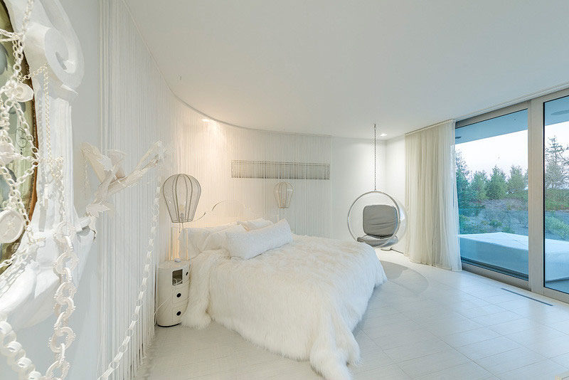 10 Examples Of Monochromatic Interiors // This all white bedroom is whimsical, with a hanging chair, hot-air balloon-shaped lamps, and curtained walls.