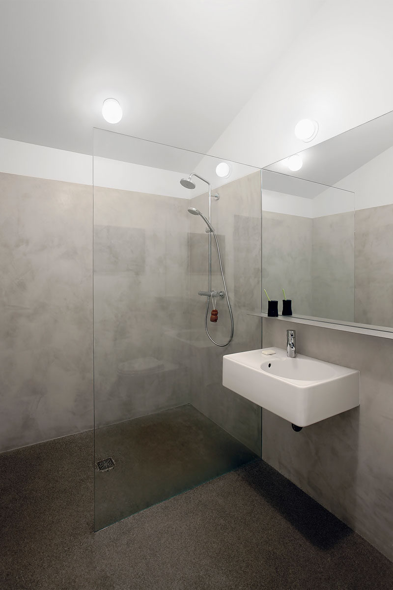 This bathroom has a pitched ceiling, and frame-less glass separates the shower from the rest of the space.