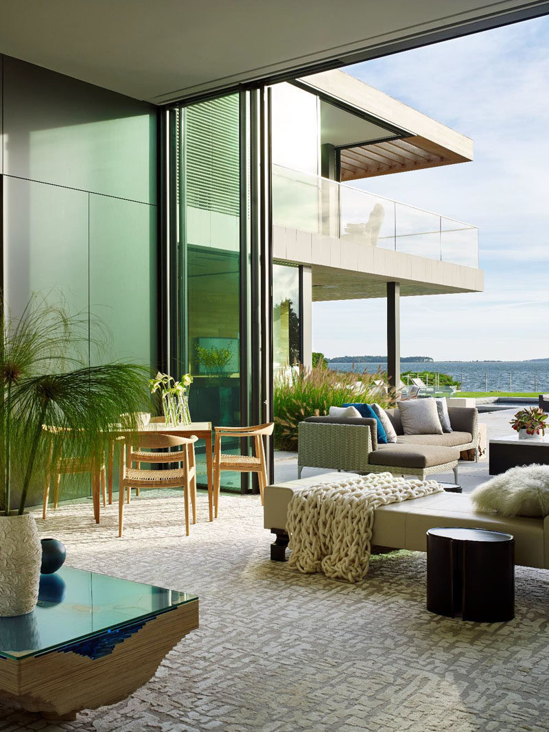 Pops of color have been added to this indoor/outdoor living room, like the blue in the coffee table and the pillow outside.