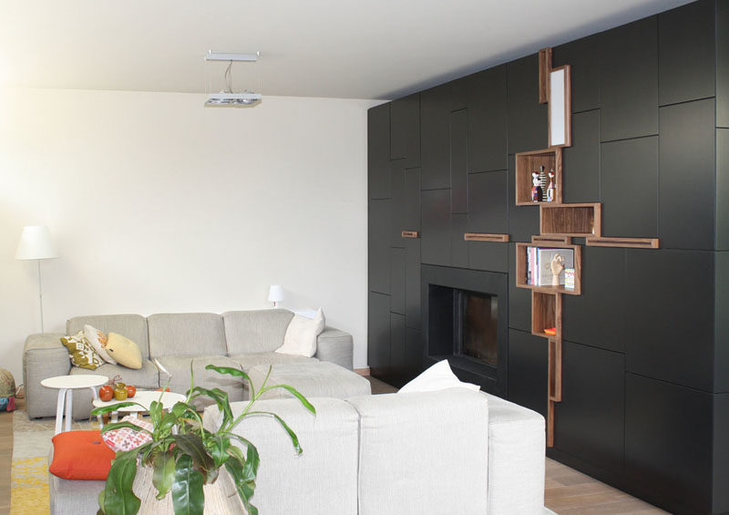 This custom-designed black cabinet surrounds the fireplace seamlessly and has some open shelves for displaying personal items.