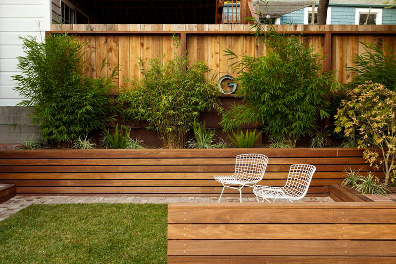 12 Ideas For Including Built-In Wooden Planters In Your Outdoor Space // These wood planters built into the side of the yard match the wood fence surrounding them to make for a cohesive backyard oasis. #WoodPlanters #BuiltInPlanters #Landscaping #LandscapeDesign #BackyardPlanters #YardIdeas