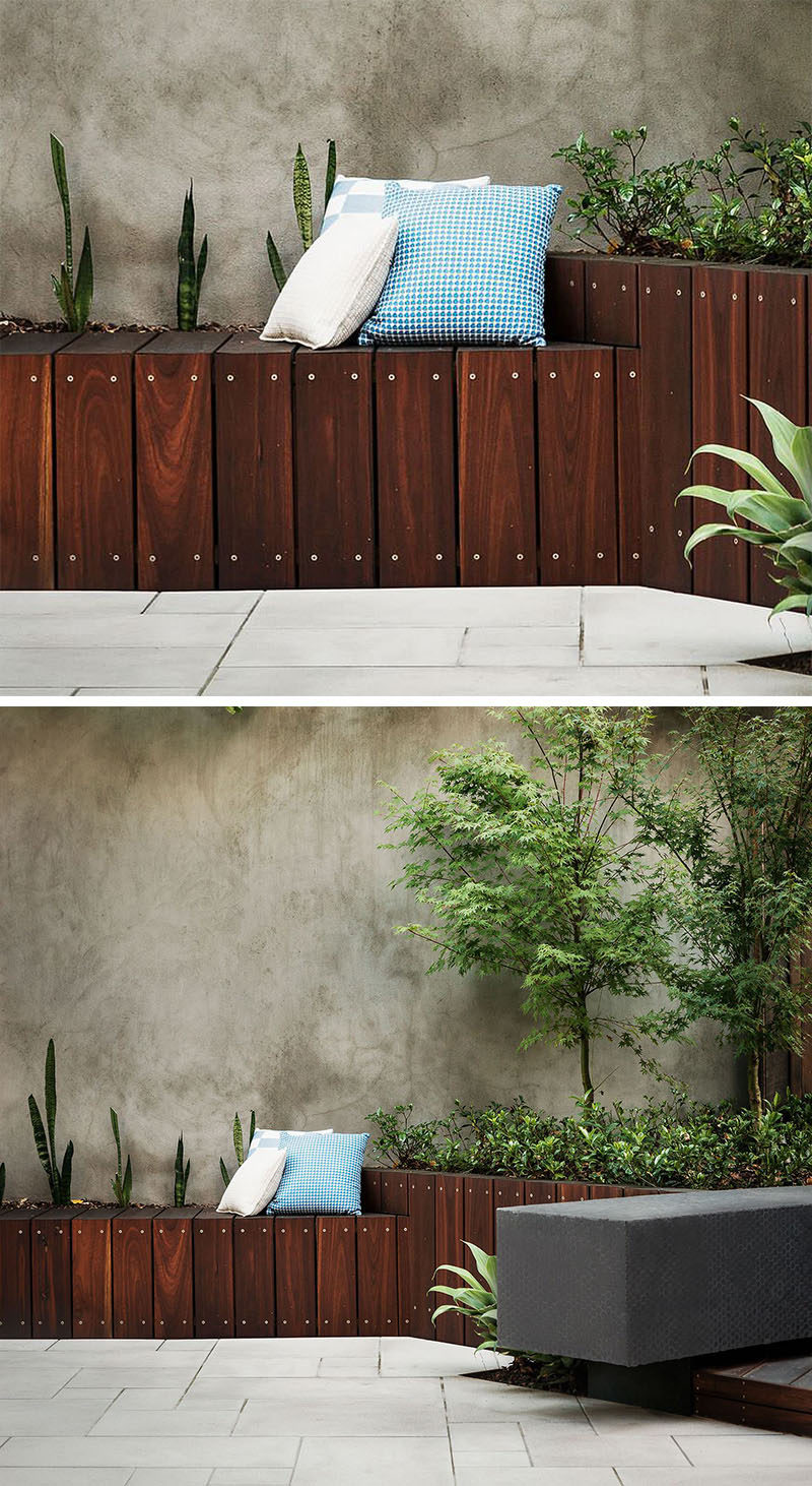 12 Ideas For Including Built-In Wooden Planters In Your Outdoor Space // The contrast between the dark wood and the concrete wall add style and functionality to the back yard in the form of seating and planters. #WoodPlanters #BuiltInPlanters #Landscaping #LandscapeDesign #BackyardPlanters #YardIdeas