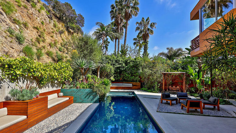 This swimming pool and outdoor area has built-in wooden seating.