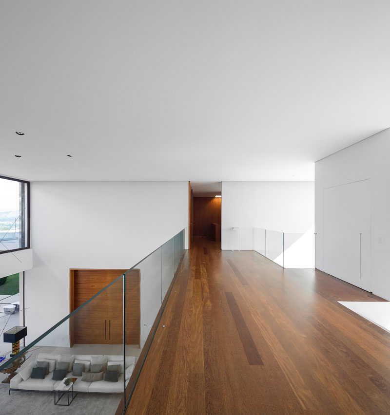 This walkway with wooden floors and glass railings, provides views of the living room below.