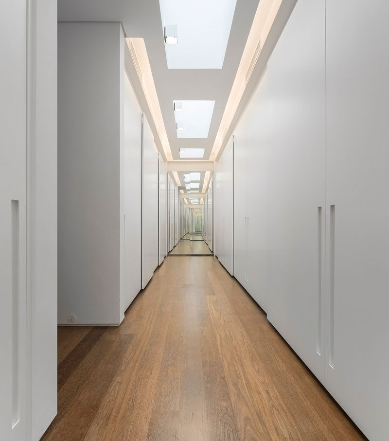 This walk-in closet has a wooden floor, and storage from the floor to the ceiling. There is also plenty of lighting and a mirror helps to make it appear as larger than it is.