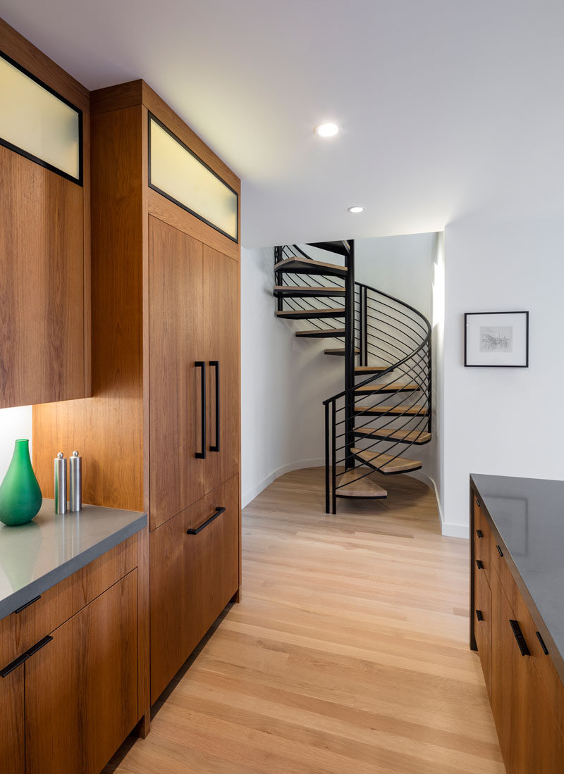 This kitchen has black hardware on wood cabinets and gray countertops.