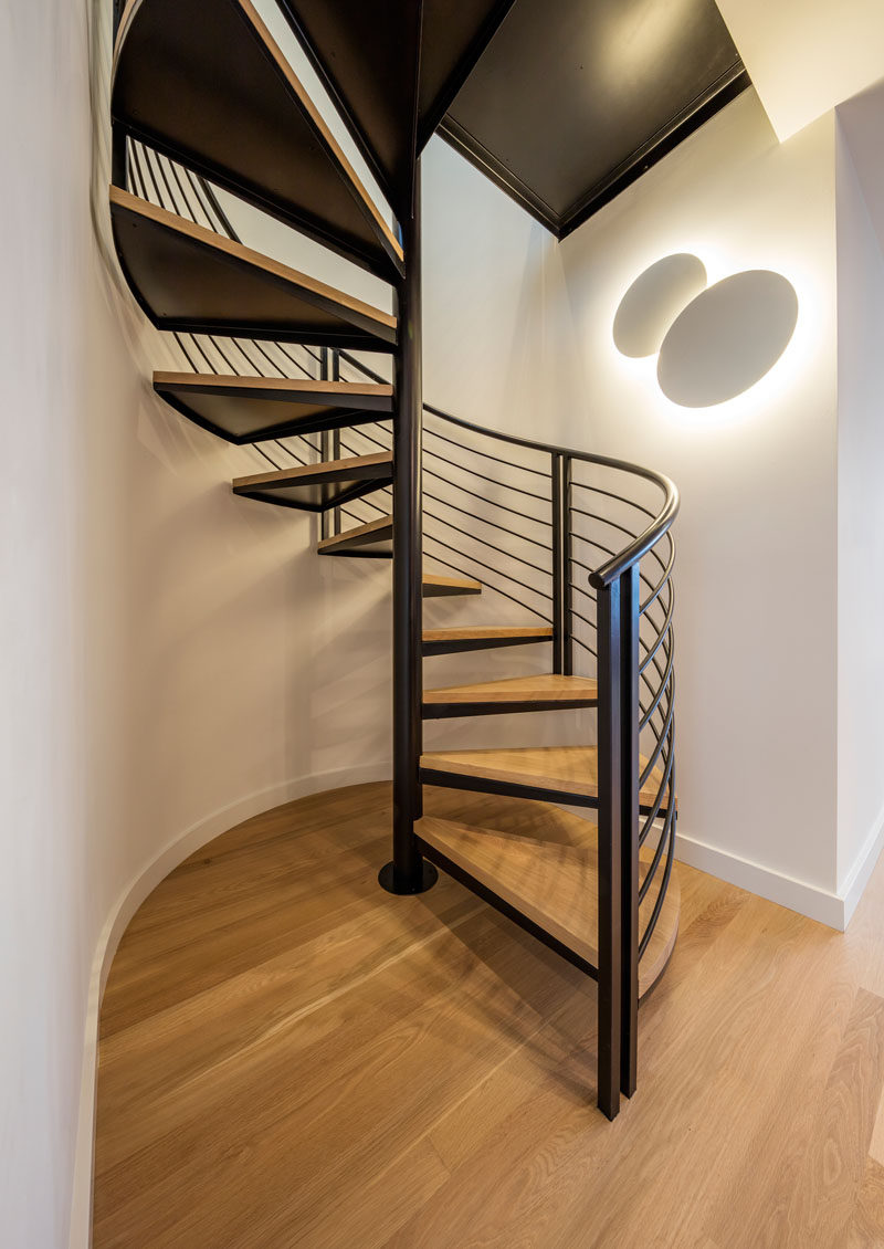 Black and wood spiral stairs are in direct contrast to the white walls.