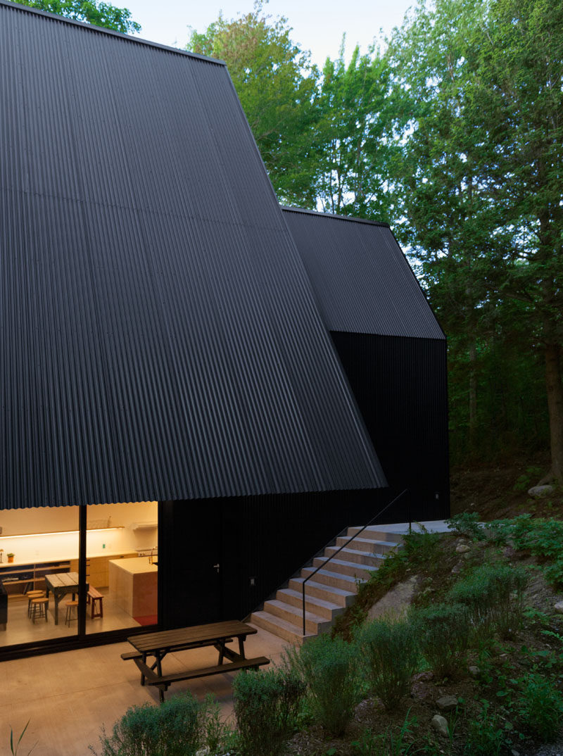 This black Canadian cottage has an overhang that covers the terrace below.