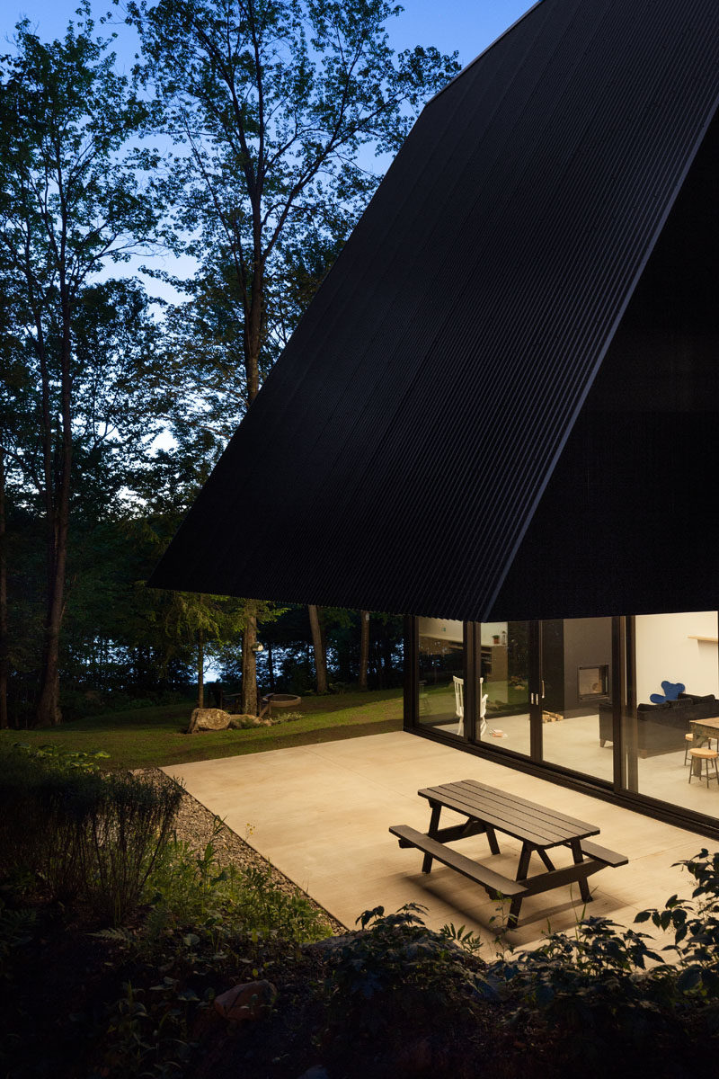 This black Canadian cottage has an overhang that covers the terrace below.