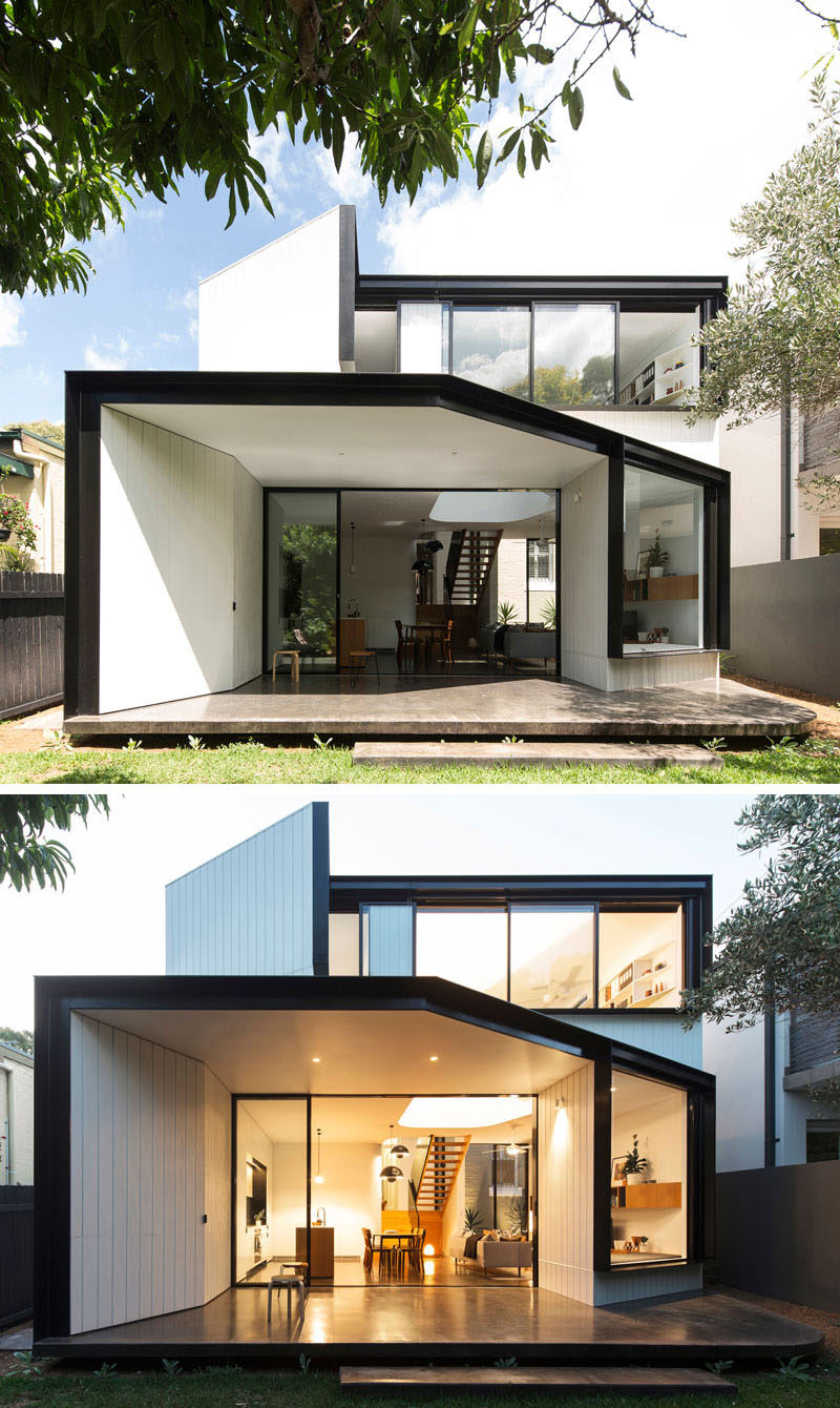 Black frames and patio contrast the white siding and interior of this house extension in Sydney, Australia.