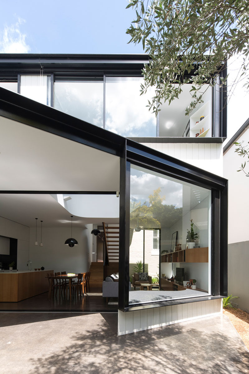 This house extension has a large window with black frames, as well as a window seat built-in on the inside.