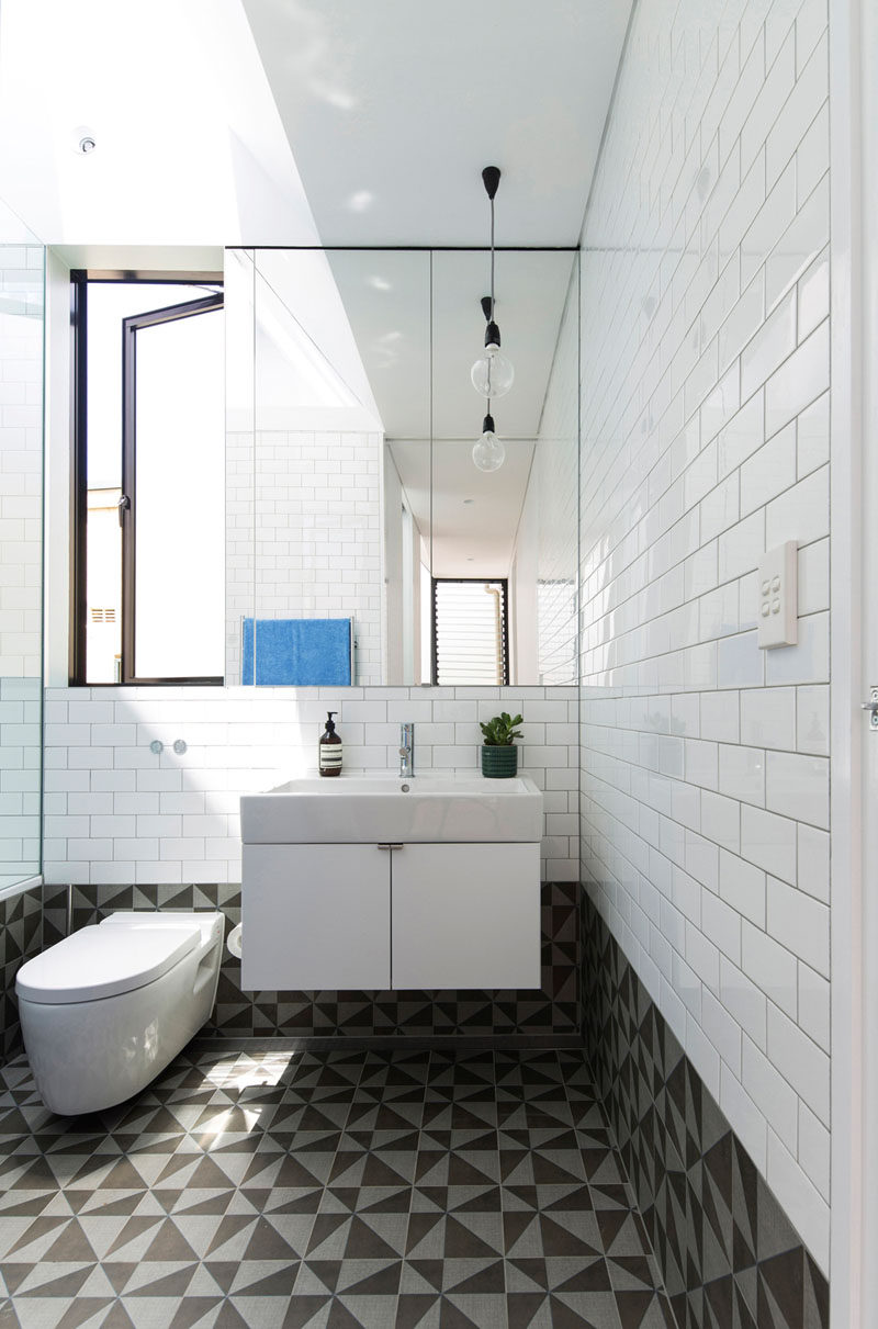 In this bathroom, white tiles match the white walls in the rest of the home, while the floor and lower portion of the walls are a bold graphic tile.