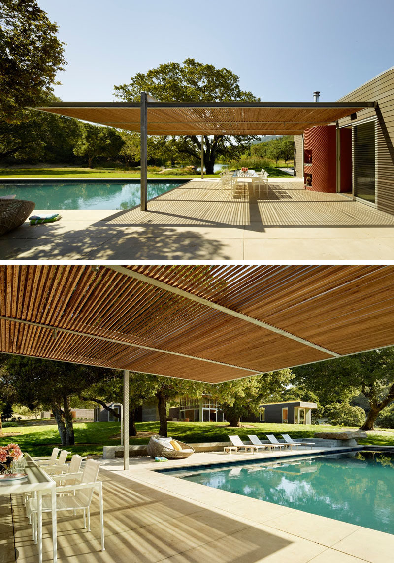 This swimming pool is surrounded by a shaded outdoor dining area, and a space for lounging in the sun.