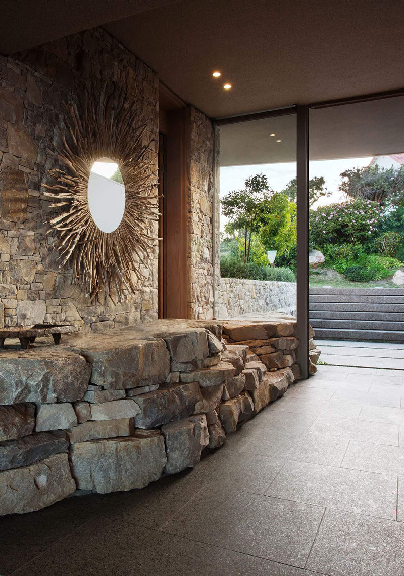 This home has a stone wall that carries from the outside through to the entryway, and a large mirror helps to reflect light.