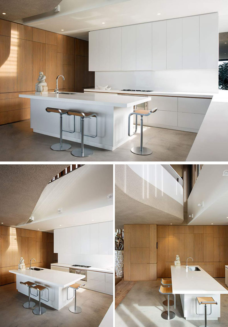 In this kitchen, the color palette is super simple, just white cabinets with touches of wood in a wall of cabinets and the counter stools. A minimal look in the kitchen has been achieved by having cabinetry without hardware.