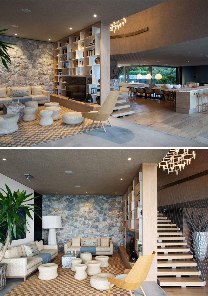 This living room has a stone feature wall and a bookshelf that separates the room from the stairs.