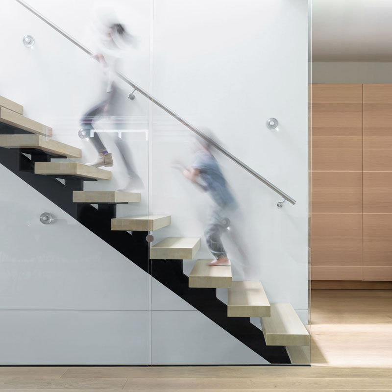 These wood and steel stairs feature a transparent glass balustrade and open risers, all of which let the light from the skylight above to flow through the space.