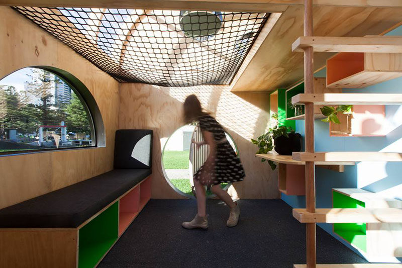 This modern playhouse (or cubbyhouse) has decorative siding and a curved roof with windows. Inside, there's bench seating, storage and loft with a net for relaxing.