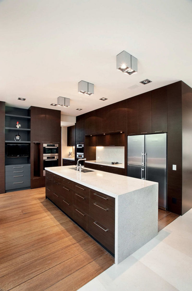 9 Inspirational Kitchens That Combine Dark Wood Cabinetry and White Countertops // This kitchen has a mix of dark wood cabinets and light wood floors, with white countertops to tie it all together.