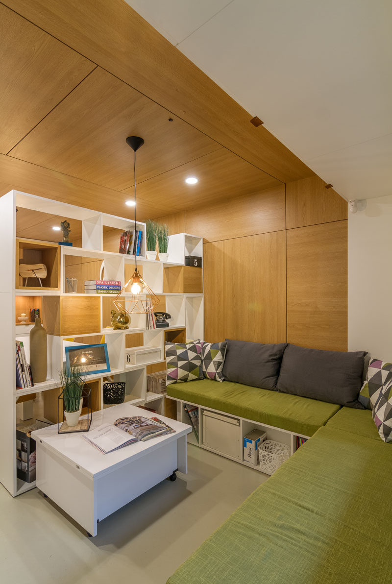 A double-sided bookshelf has been used as a room divider, with some sections blocked off with wooden boxes, providing cubby holes for decorative items.