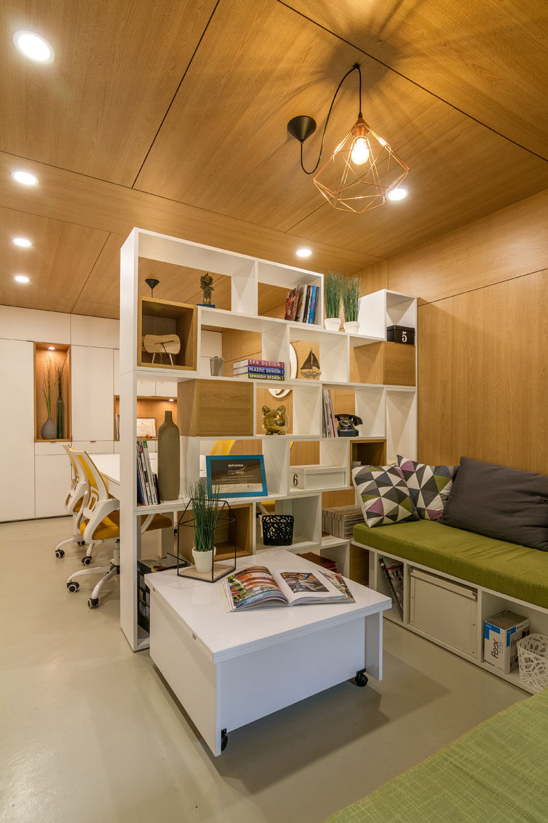 A double-sided bookshelf has been used as a room divider, with some sections blocked off with wooden boxes, providing cubby holes for decorative items.