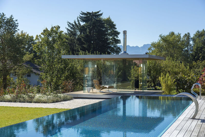 This contemporary glass pool house has uninterrupted views, sliding doors on all sides, a hanging fireplace and a hidden fridge in the floor.