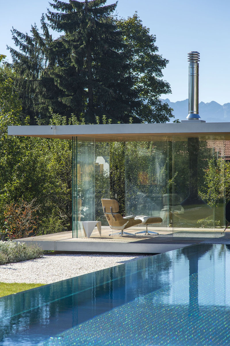 This contemporary glass pool house has uninterrupted views, sliding doors on all sides, a hanging fireplace and a hidden fridge in the floor.