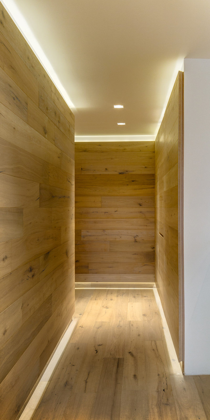 This wood covered hallway has hidden lighting to light the way.