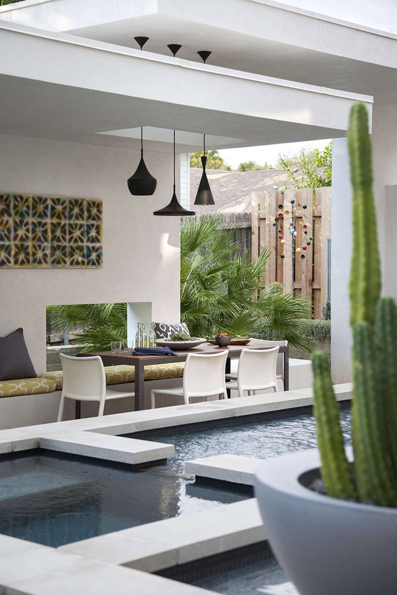 This contemporary pool house has a dining table and bench seating.