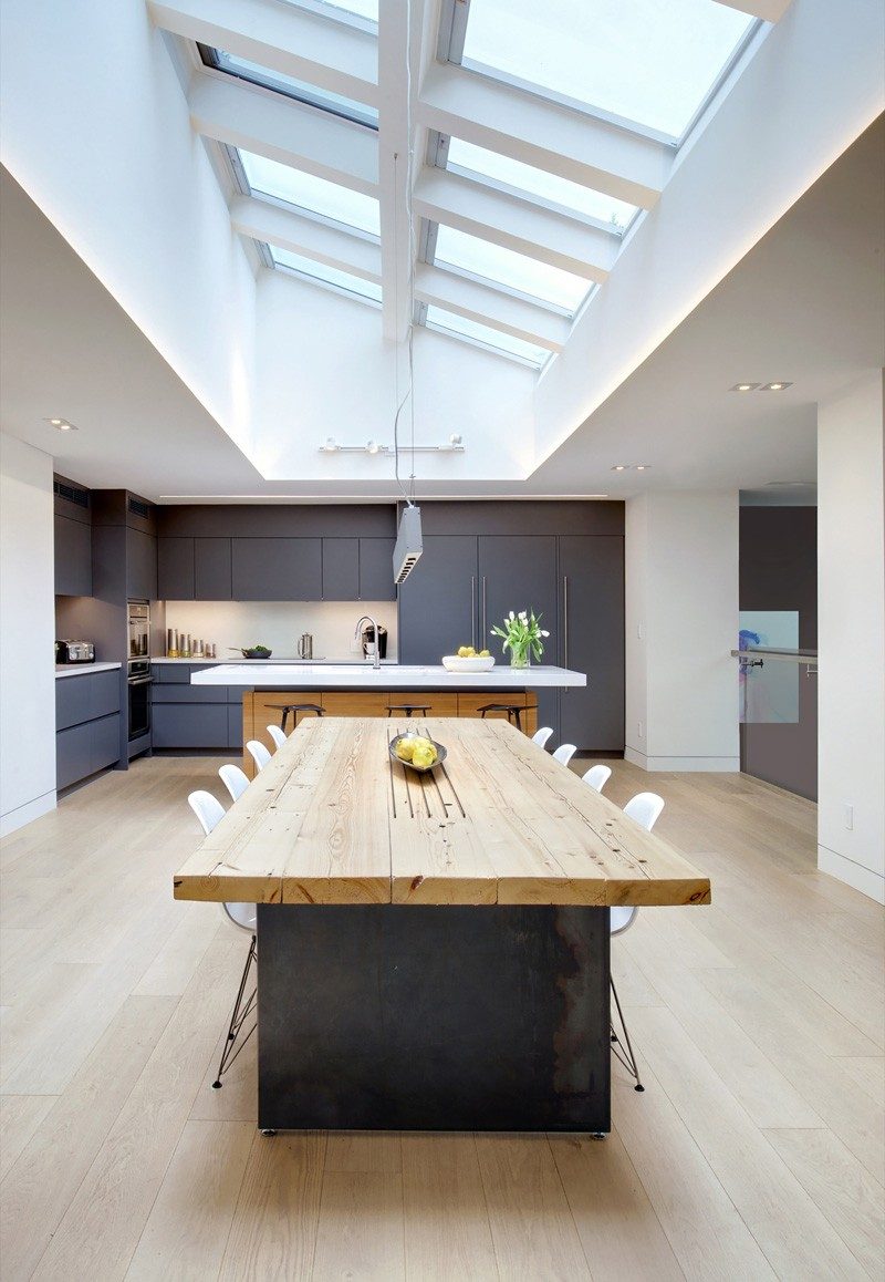 This home features a large wood and steel dining table with the ceiling covered in skylights.