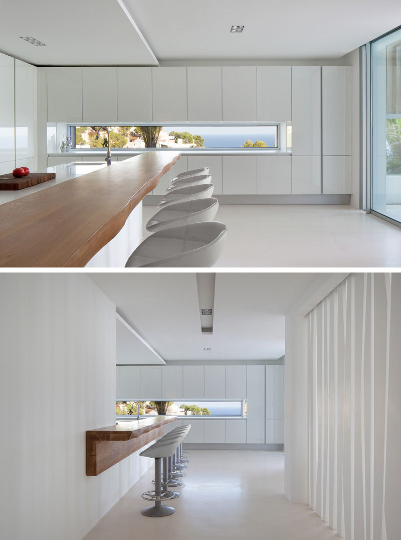 12 Inspirational Examples Of Letterbox Windows In Kitchens // This letterbox window sits level with the countertop in this Ibiza home, and provides an incredible view of the ocean and adds brightness to the all white kitchen.