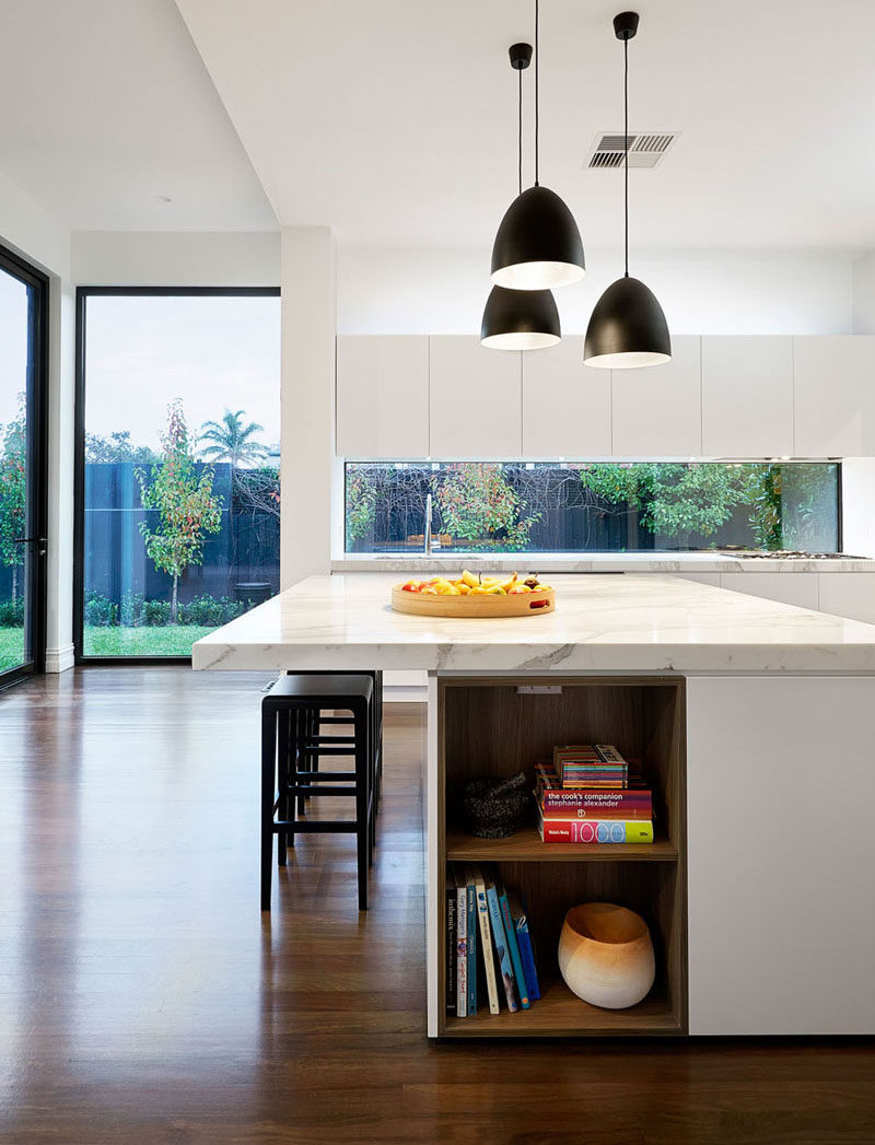 12 Inspirational Examples Of Letterbox Windows In Kitchens // White cabinetry, white walls, and a marble countertop, all partnered with the long letterbox window work together in this kitchen to make it super bright and welcoming.