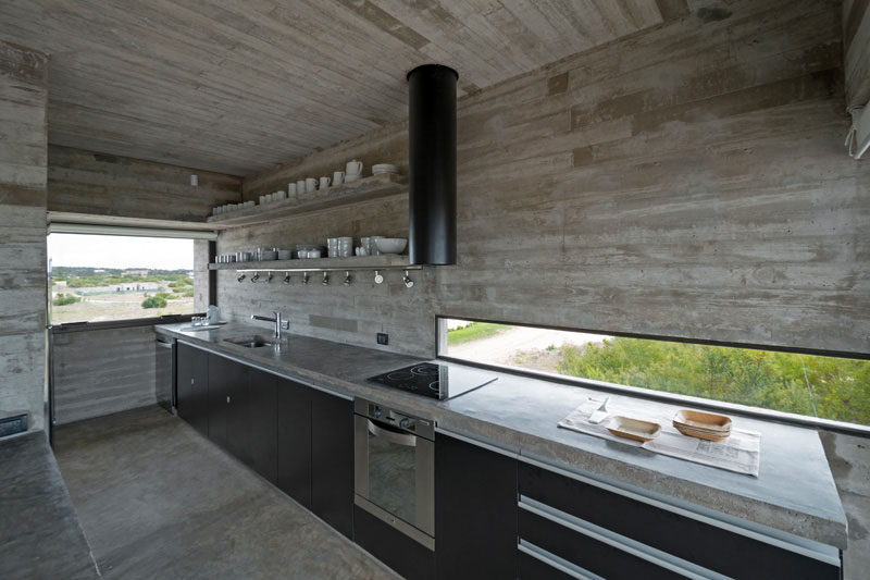 12 Inspirational Examples Of Letterbox Windows In Kitchens // This skinny letterbox window brightens up the dark black cabinets and concrete used throughout this kitchen, and looks out over the nearby golf course.