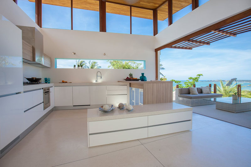 12 Inspirational Examples Of Letterbox Windows In Kitchens // While the kitchen of this villa didn't necessarily need the light from the letterbox window, it acts as an art piece, providing views of the blue sky and green palm leaves.