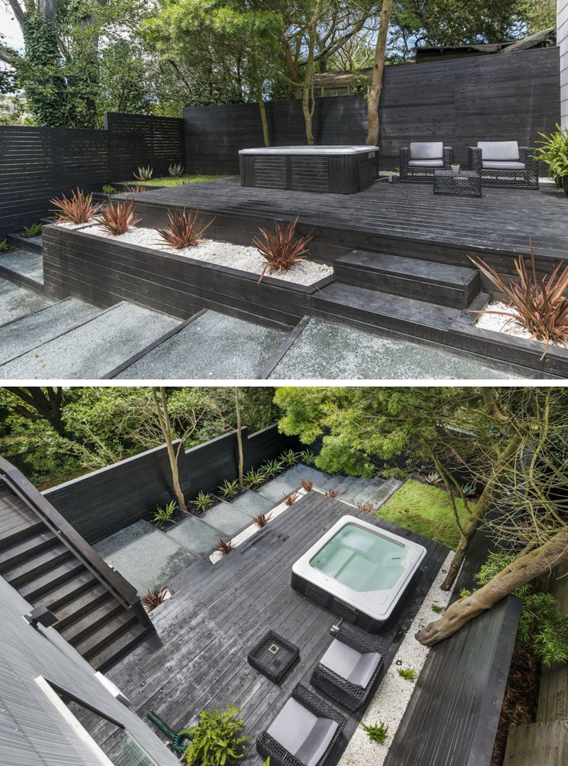 13 Multi-Level Backyards To Get You Inspired For A Summer Backyard Makeover // This backyard has created multiple levels through the use of black wood to make steps, planters, and an elevated deck with an entertaining spot and a hot tub.