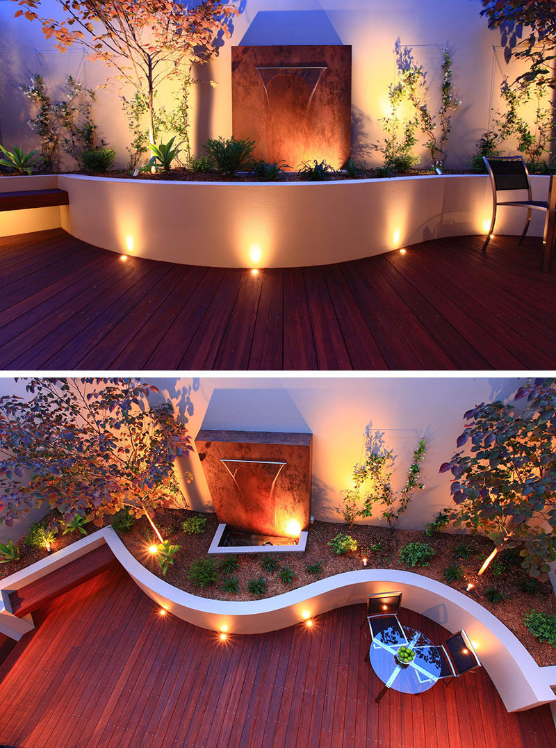 17 Inspiring Examples Where Exterior Uplighting Has Been Used To Show Off A House // Recessed lighting on this curved patio and inside the planters brighten the outdoor space and create a dramatic effect with the shadows behind the plants and metal installation.