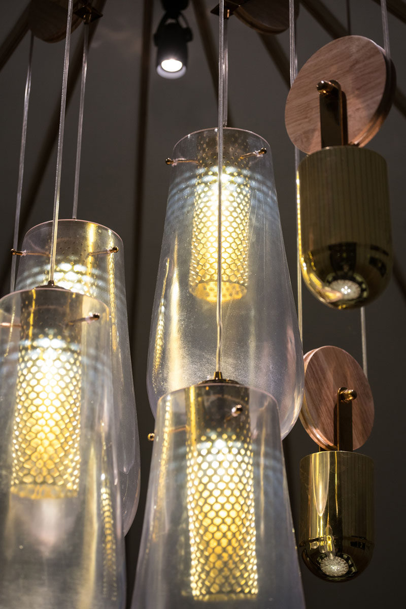 The custom-designed pendant lights that are on a pulley system, consist of a drop pendant light made from cast resin, a counterweight made from cast concrete, and brass details with a diffused COB LED light within.