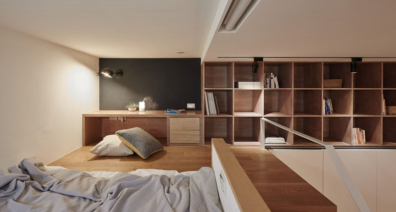 In this small apartment, there's s a small built-in desk area, and above the wardrobe, there are exposed shelves for additional storage.