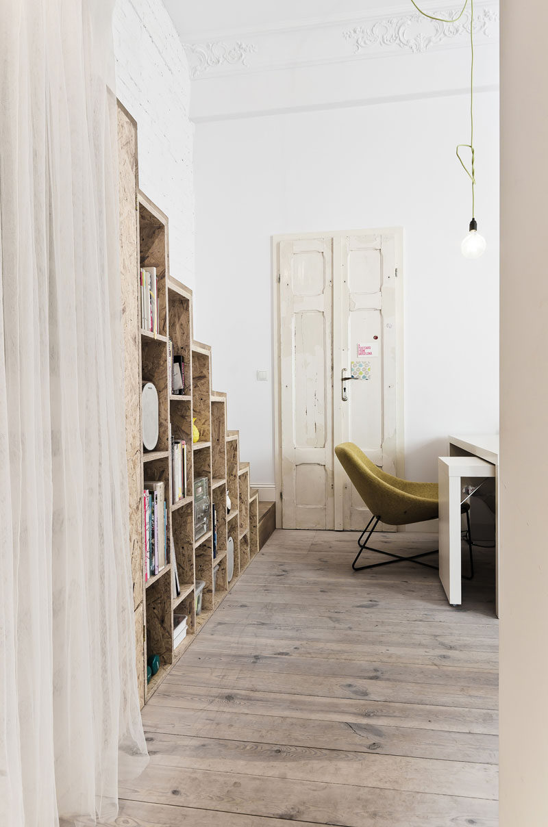 These wooden stairs in a small apartment, have an open bookshelf built into them.