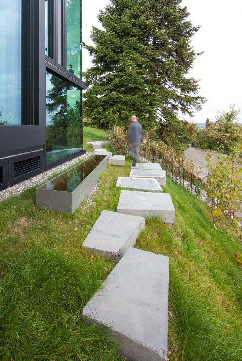 10 Ideas for Stepping Stones in Your Garden // Large concrete stepping stones line the side of this sloping yard making for an easy path around the house.