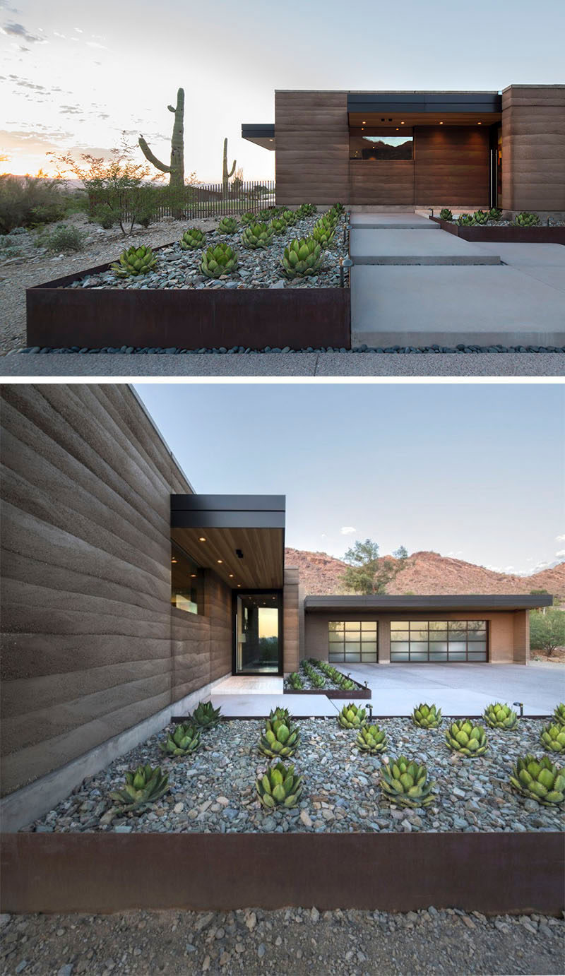 9 Ideas For Including Weathering Steel Planters In Your Garden // The rows of succulents and large rocks within these weathered steel planters help make the front of this desert house welcoming and up the house's curb appeal. #SteelGardenPlanters #WeatheredSteelPlanters #CortenSteelPlanters #Landscaping #GardenIdeas #PlanterIdeas