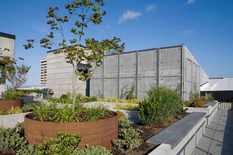 9 Ideas For Including Weathering Steel Planters In Your Garden // The round steel planters inside the even larger concrete planters create depth and add texture to the gardens on this outdoor patio.  #SteelGardenPlanters #WeatheredSteelPlanters #CortenSteelPlanters #Landscaping #GardenIdeas #PlanterIdeas