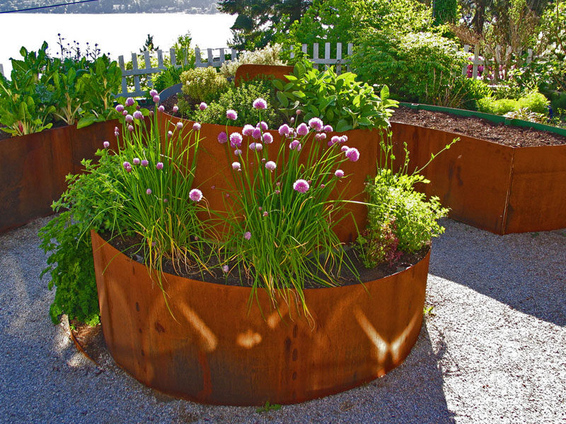 9 Ideas For Including Weathering Steel Planters In Your Garden // This weathered steel planter spirals out of the ground to add height and an artistic touch to the garden. #SteelGardenPlanters #WeatheredSteelPlanters #CortenSteelPlanters #Landscaping #GardenIdeas #PlanterIdeas