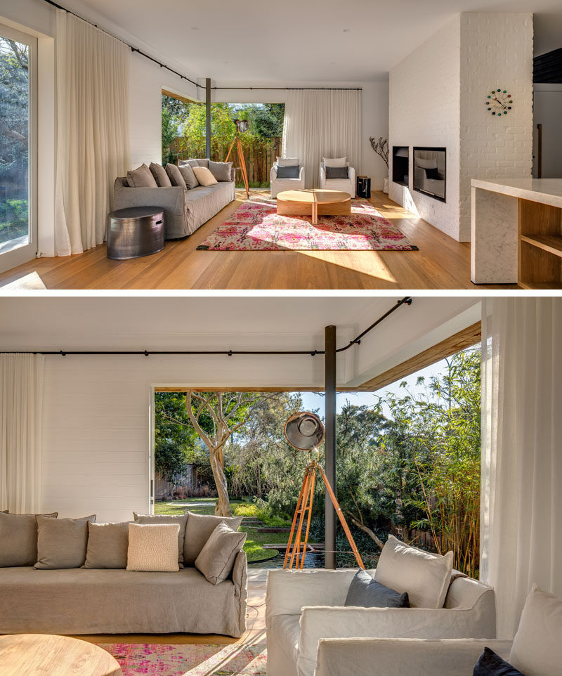 Inside this Australian home, the living area, dining and kitchen all share the same space that's open to the backyard. A built in fireplace and television make for a cozy living room, and when it gets too sunny, curtains can be drawn to provide shade.