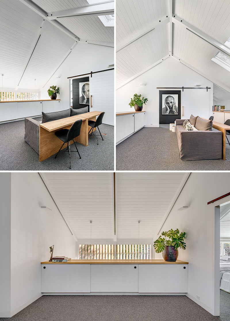 This upstairs lounge area has exposed beams, barn doors, a pitched roof and skylights.