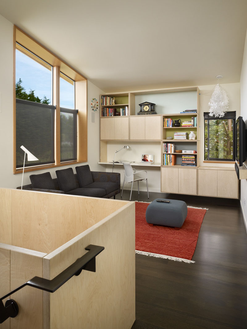 In this living room, there's a built-in home office, and windows providing lots of natural light. Half-blinds have been added to the windows facing the street for privacy.