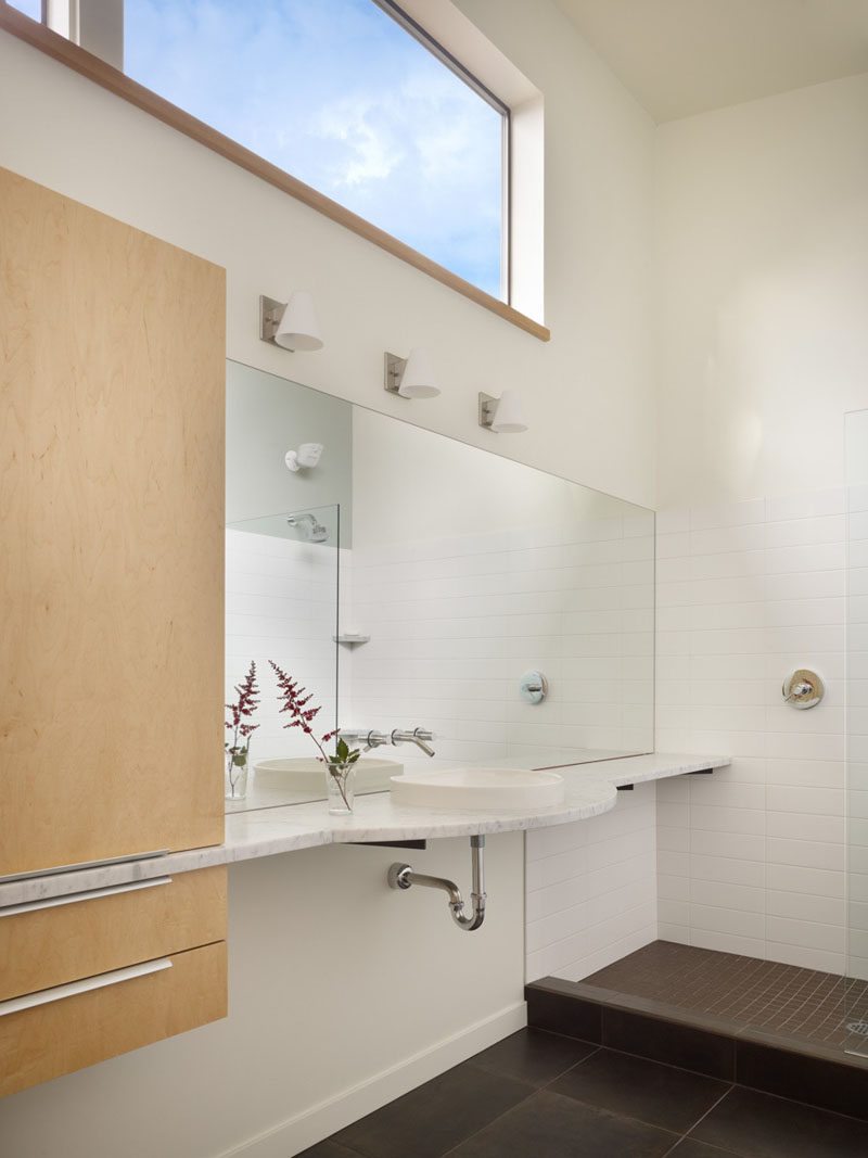 In this bathroom, the window lets in plenty of light, and the vanity runs the length of the wall, cutting through the cabinetry.