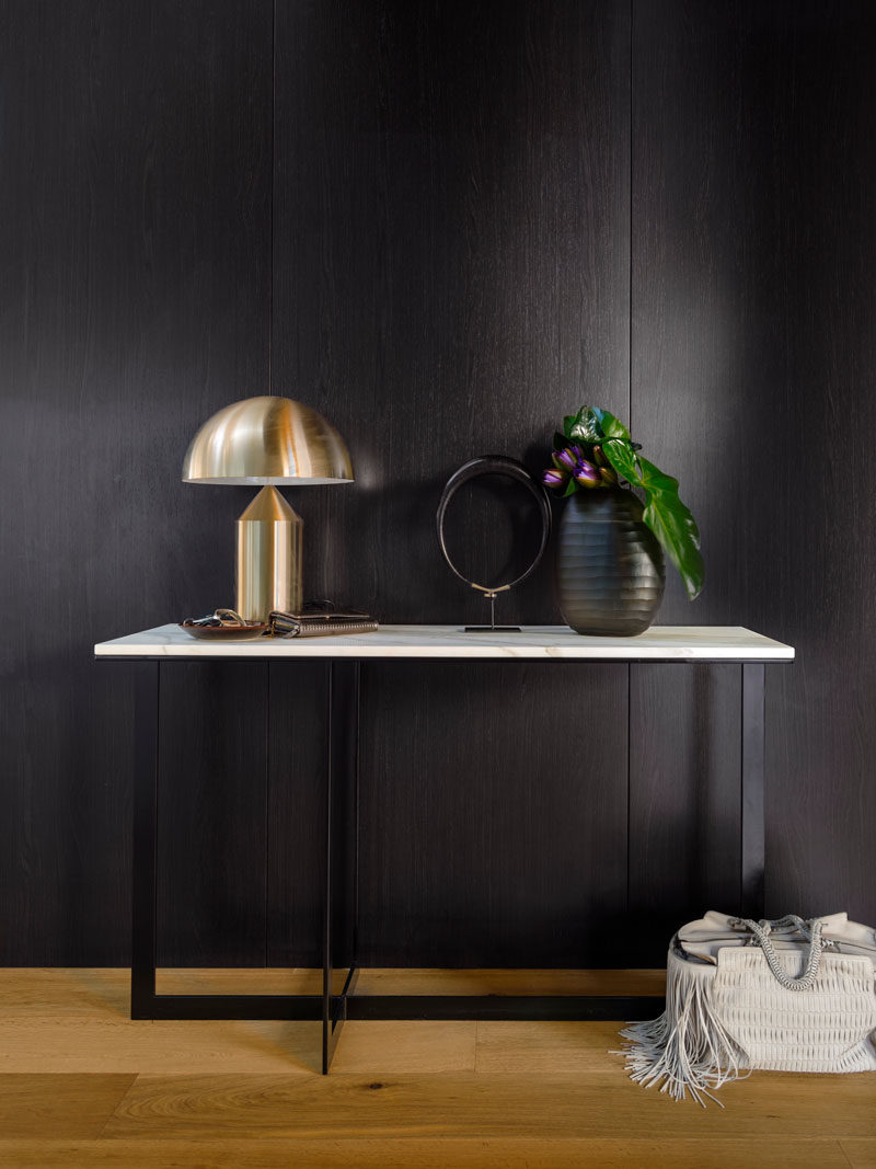 Elegant touches are scattered throughout this home, like this black and marble table against the wall, decorated with personal decor items.